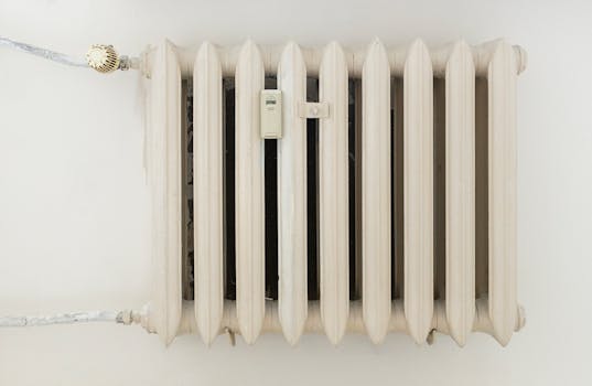 A classic white metal radiator on a plain wall, showcasing minimalist interior design.
