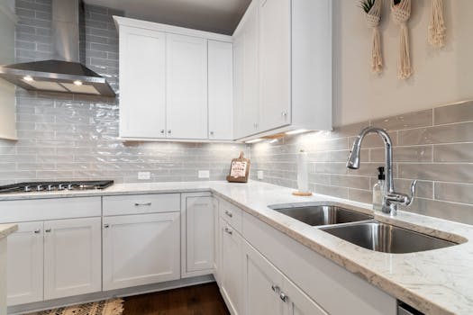 Sleek white kitchen with marble countertops and modern fixtures.
